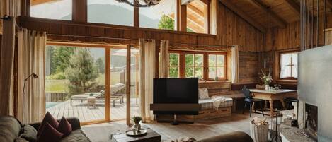 A spacious living room with a large TV, wooden furniture, and a fireplace.