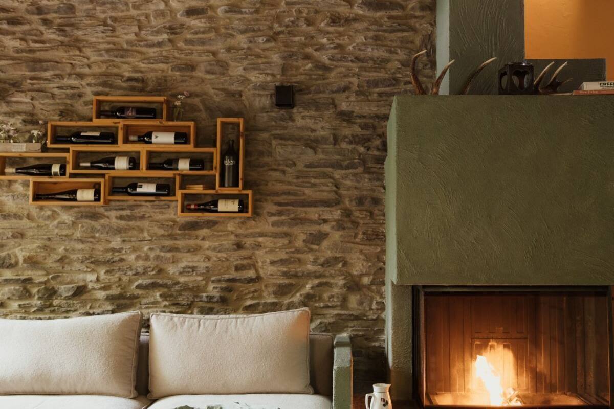 A cozy room with a stone wall, a fireplace, and wooden wine racks.