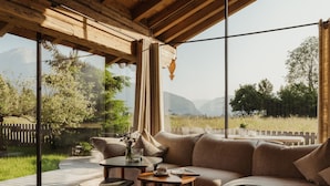 Une pièce chaleureuse avec un plafond en bois, de grandes fenêtres, un canapé et une petite table.