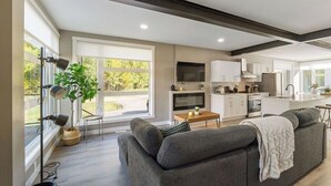 A modern kitchen with white cabinets, a central island, and a dining area. - Modern Home and guest house in peaceful location. (Alberta Beach)