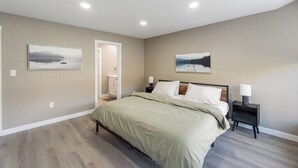 A bedroom with a bed, nightstands, and two wall-mounted lamps. - Modern Home and guest house in peaceful location. (Alberta Beach)