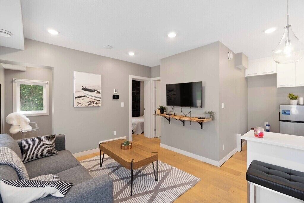 Ein modernes Wohnzimmer mit einer Couch, einem Couchtisch und einem an der Wand befestigten Fernseher.