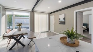 A modern living room with a large window, a dining table, and a sofa. - Modern Home and guest house in peaceful location. (Alberta Beach)