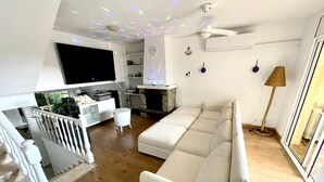 A modern living room with a white sofa, a flat-screen TV, a fireplace, and a staircase. - HOUSE IN MASNOU NEXT TO BEACH AND TRAIN (El Masnou)