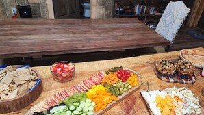 A wooden table with various food items including sliced apples, grapes, cucumbers, and cheese. - Rustic Comfort Cabins-Anglers Basin with Hot Tub (Amity)