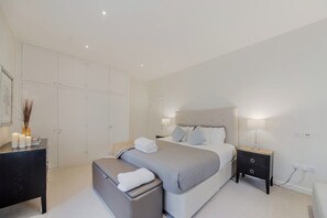 Une chambre à coucher moderne, avec un lit, des tables de chevet, un bureau et une armoire.