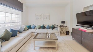 Una sala de estar moderna con un sofá modular, una mesa de centro, un televisor y una estantería.