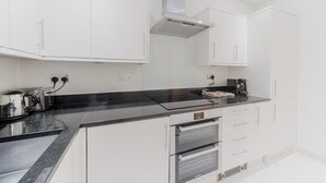 Una cocina moderna con armarios blancos, encimera negra y hornos empotrados.