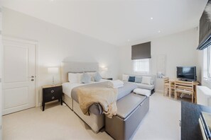 A modern bedroom with a bed, bedside tables, a desk, and a television. - Mayfair Oxford Street by Estatesmen (London)