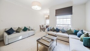 A modern living room with a sofa set, a coffee table, and a dining area in the background. - Mayfair Oxford Street by Estatesmen (London)