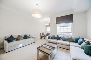 A modern living room with a sofa set, a coffee table, and a dining area in the background. - Mayfair Oxford Street by Estatesmen (London)
