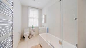 A modern bathroom with a bathtub, toilet, and sink. - Mayfair Oxford Street by Estatesmen (London)