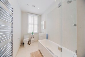 A modern bathroom with a bathtub, toilet, and sink. - Mayfair Oxford Street by Estatesmen (London)