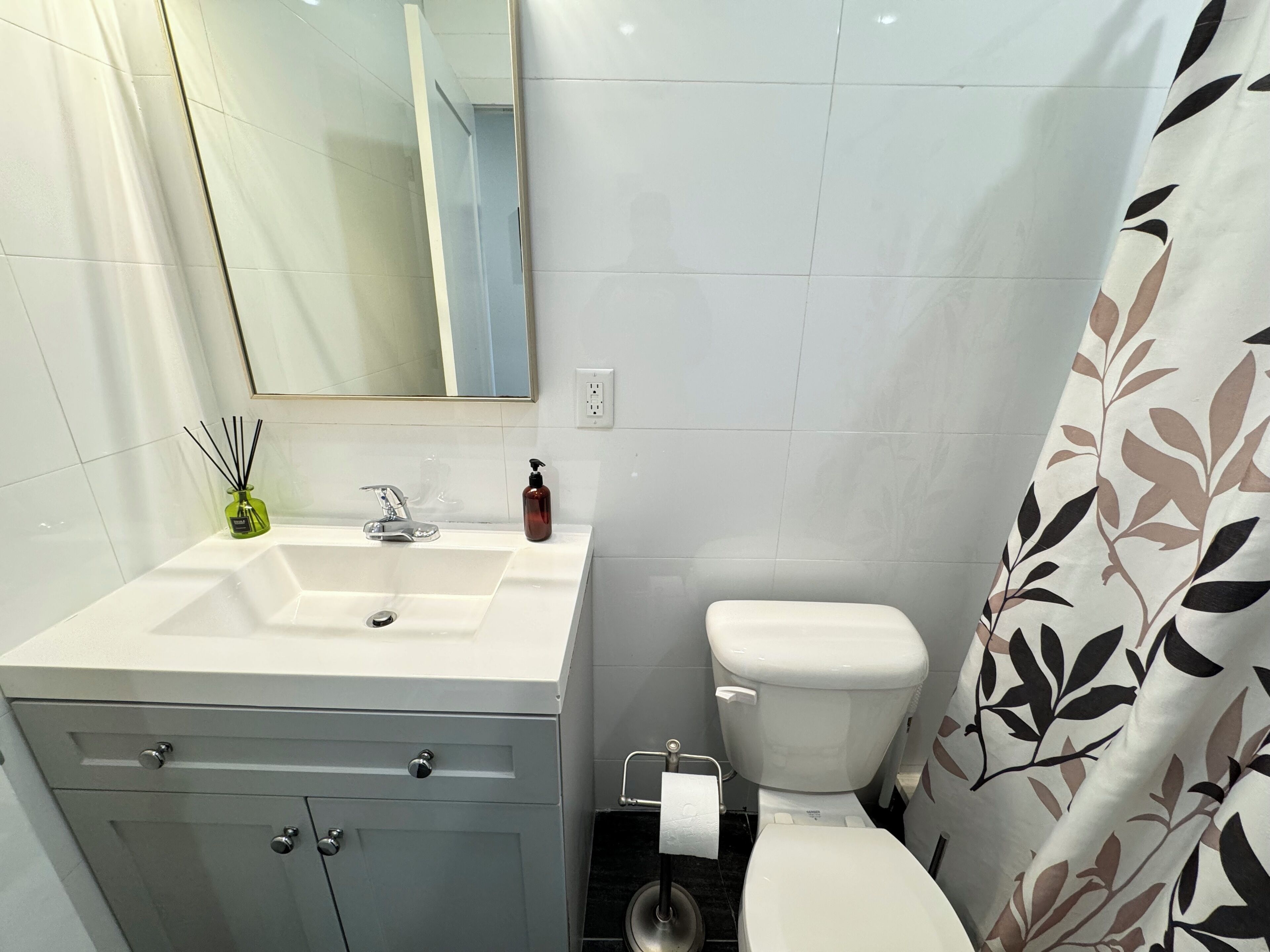 Une salle de bain avec un lavabo blanc, un miroir et des toilettes.