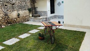 Um pátio com parede de pedra, um banco de madeira, uma bicicleta e um vaso de planta.