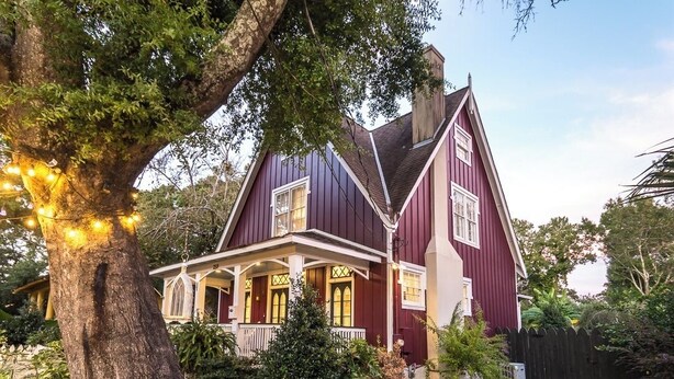 A large, two-story house with a steep gable roof, a front porch, and a well-maintained garden. - Charming 3-bedroom cottage in Oakleigh Historical District in downtown Mobile (Mobile)