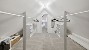 Un corridoio stretto e bianco con soffitto spiovente, che conduce a una camera da letto.