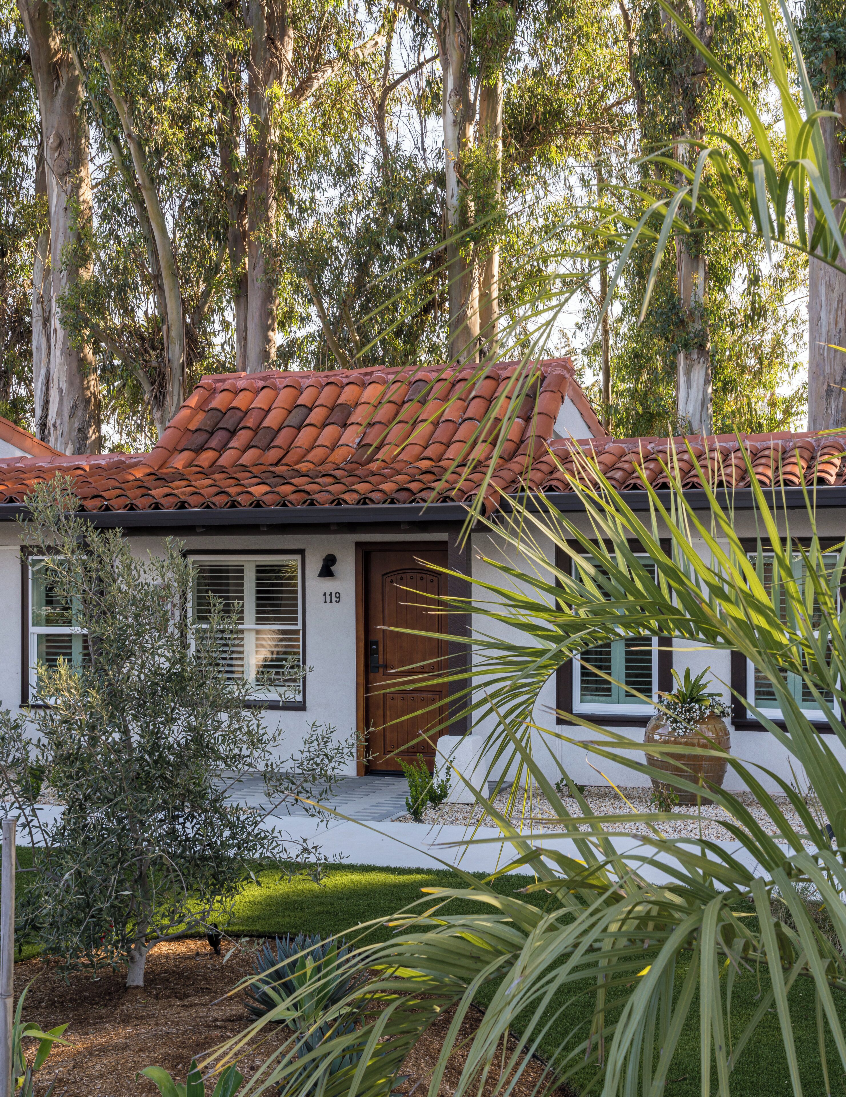 A house with a red-tiled roof, a wooden door, and a number 119 on the wall.