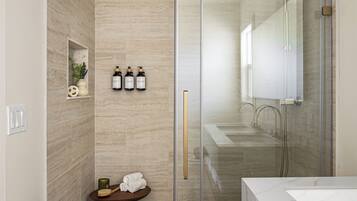 Een moderne badkamer met een glazen douchecabine, een wastafel met spiegel en een toilet.