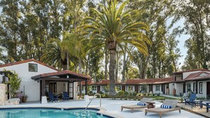 A pool area with lounge chairs, a covered seating area, and a house with a tiled roof. - Casia Inn (Sonoma)
