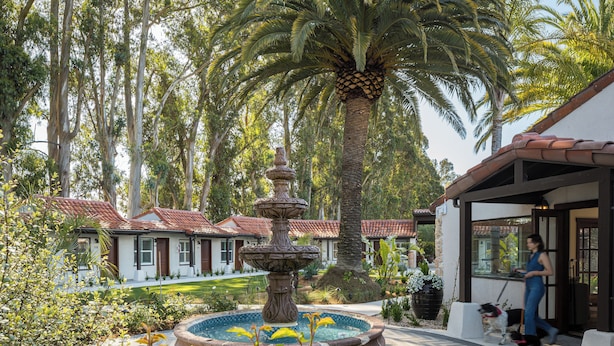 A courtyard with a fountain, palm trees, and a building with a red-tiled roof. - Casia Inn (Sonoma)