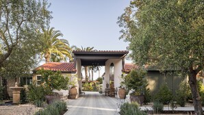 A pathway leading to a house with a tiled roof, surrounded by various plants and trees. - Casia Inn (Sonoma)