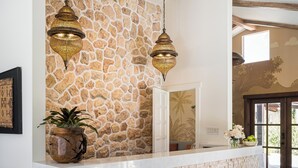 A reception area with a stone wall, wooden beams, and hanging lamps. - Casia Inn (Sonoma)