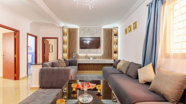 A modern living room with a sofa set, a coffee table, and a flat-screen TV mounted on the wall.