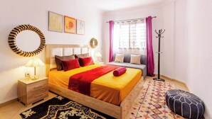 A bedroom with a bed, bedside table, lamp, and a window with curtains.