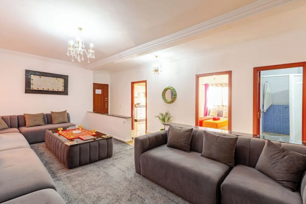 A modern living room with a sectional sofa, a coffee table, and a chandelier.