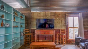 A rustic living room with a wooden desk, two chairs, a television, and a bookshelf. - Leaning Tower of Alpine (Alpine)
