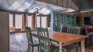 A spacious room with a wooden dining table and chairs, a ceiling fan, and a bookshelf filled with various items. - Leaning Tower of Alpine (Alpine)