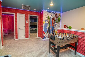A room with a red brick wall, a foosball table, and a mural of Mario and Luigi. - GO 35 - Windsor CAY (Clermont)