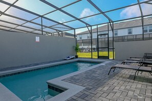 En indendørs swimmingpool med kig til det fri, flisegulv og et par liggestole.