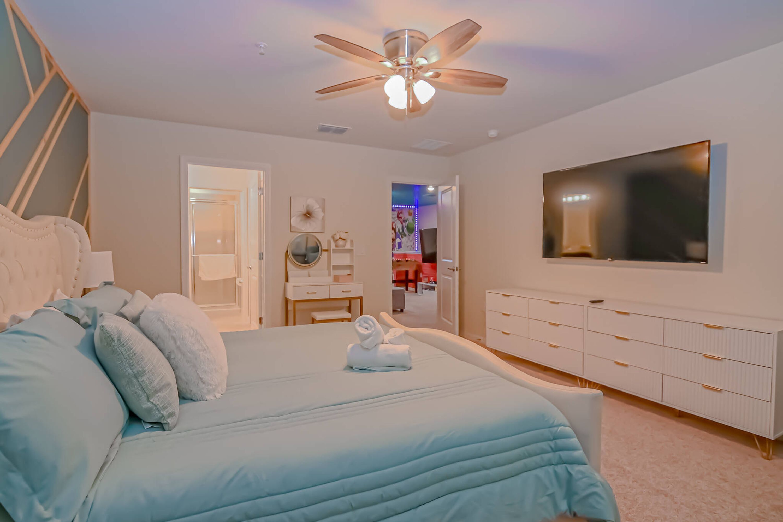 A bedroom with a bed, a ceiling fan, a TV, and a dresser.
