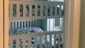 Ein Etagenbett mit floralem Bettbezug, eine weiße Tür und eine Deckenleuchte.