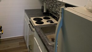Eine kleine Küche mit weißen Schränken, einem Herd und einem Kühlschrank.