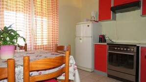 Une cuisine équipée d’une table à manger, de chaises, d’un réfrigérateur, d’une cuisinière et d’une plante en pot.