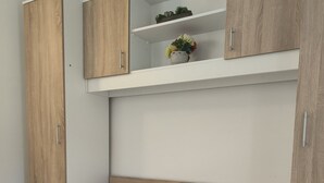 Une chambre à coucher avec un lit, une armoire en bois et une étagère ornée d’objets décoratifs.