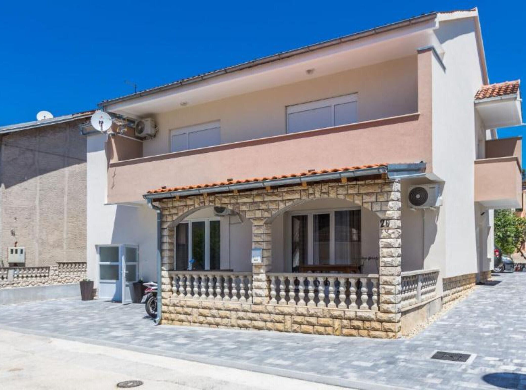 A two-story building with a balcony and a stone facade.