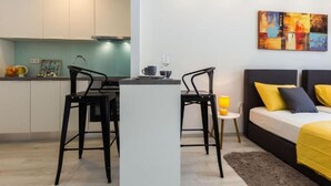 A modern apartment with a kitchen, dining area, and a bed with yellow bedding. - Charming Zadar Apartment Near Old Town with Convenient Access to Beaches Apartman ( 2 ) (Zadar)