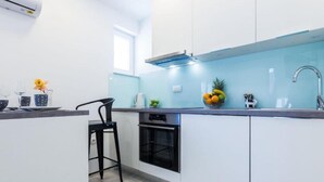 A modern kitchen with white cabinets, a black oven, and a blue backsplash. - Charming Zadar Apartment Near Old Town with Convenient Access to Beaches Apartman ( 2 ) (Zadar)