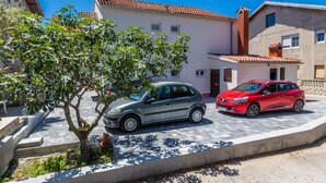A residential street with two parked cars, a tree, and buildings with red-tiled roofs. - Charming Zadar Apartment Near Old Town with Convenient Access to Beaches Apartman ( 2 ) (Zadar)