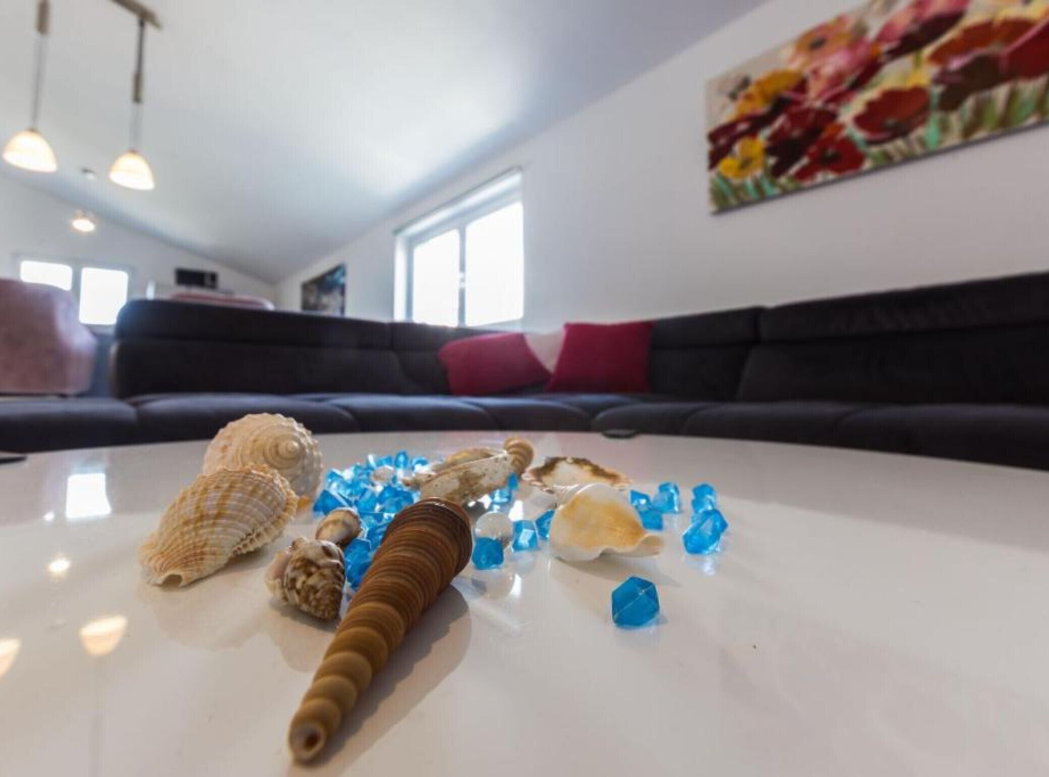 Ein weißer Tisch mit Muscheln und blauen Glasstücken.
