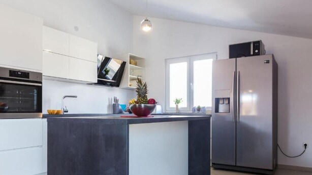 A modern kitchen with a central island, built-in oven, and a refrigerator.