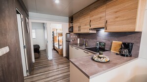 A modern kitchen with wooden cabinets, a countertop with a coffee maker, and a dining area visible in the background.