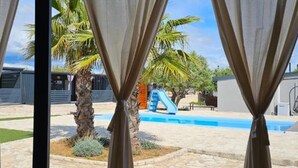 A pool area with a slide, palm trees, and a stone pathway.