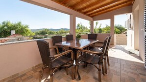Un patio al aire libre con techo de madera, una mesa y sillas de mimbre.