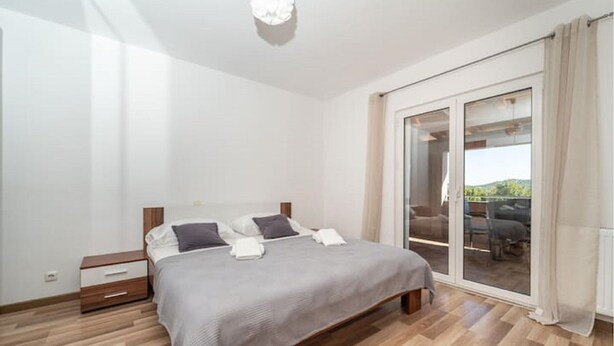 Un dormitorio con cama, mesita de noche y puerta corrediza de vidrio que da a un espacio exterior.