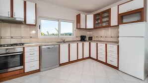 Una cocina moderna con armarios blancos, horno integrado, lavavajillas y refrigerador.